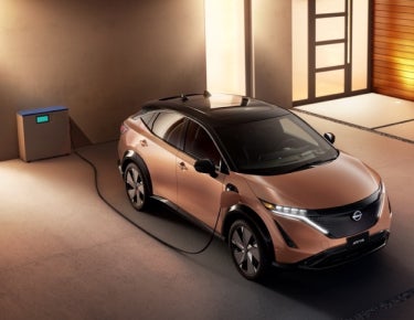 Nissan ARIYA plugged-in and charging outside a home | Fort Collins Nissan in Fort Collins CO